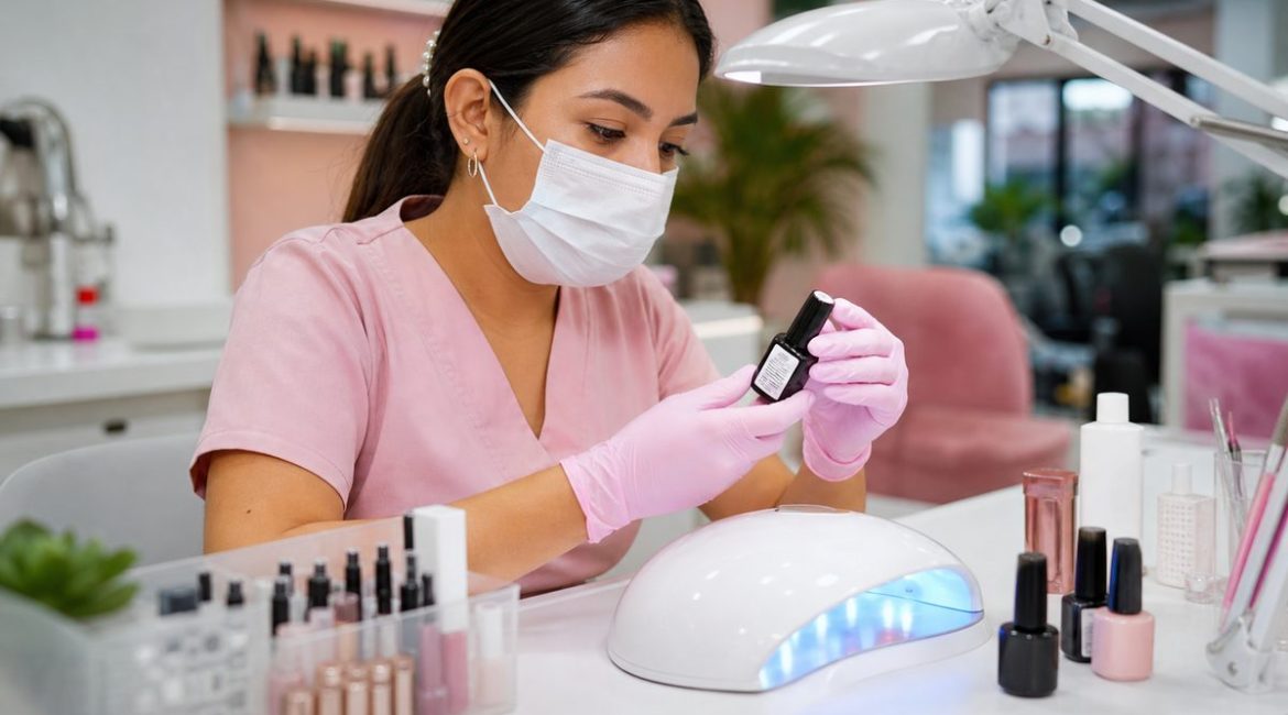 Manicurista profesional revisando etiqueta de esmalte semipermanente en salón de uñas en Colombia